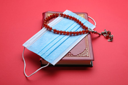 Muslim prayer beads, Quran and medical mask on red backgroundの写真素材