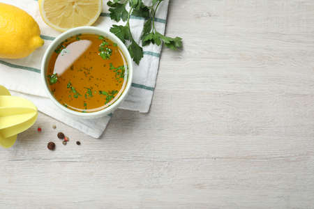 Bowl of lemon sauce and ingredients on white wooden table, flat lay with space for text. Delicious salad dressingの写真素材