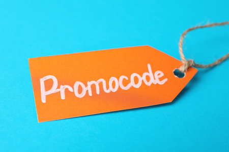 Tag with words Promo Code on light blue background, closeup