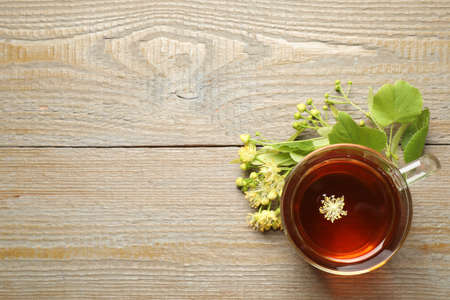 Cup of tea and linden blossom on wooden table, flat lay. Space for textの写真素材