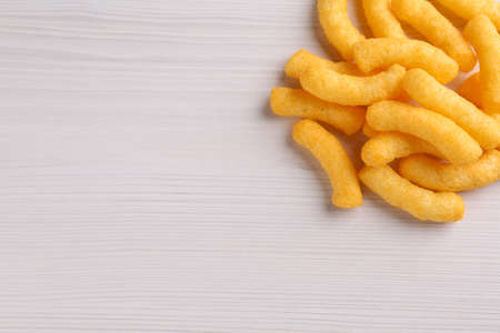 Heap of tasty cheesy corn puffs on white wooden table, flat lay. Space for textの写真素材