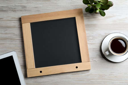 Clean small chalkboard, coffee, plant and tablet on light wooden table, flat layの写真素材