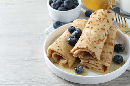 Delicious crepes with blueberries and honey on white wooden table. Space for textの写真素材