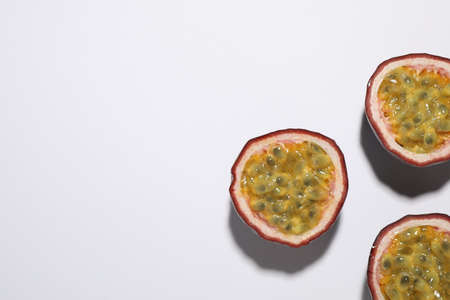 Halves of passion fruits (maracuyas) on white background, flat lay. Space for textの写真素材