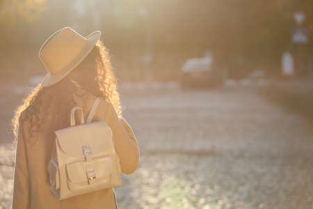 African-American woman with stylish beige backpack on city street, back view. Space for textの写真素材