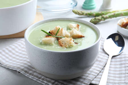 Bowl of delicious asparagus soup on light gray tableの写真素材