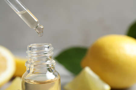 Citrus essential oil dripping from pipette into bottle, closeup. Space for textの写真素材