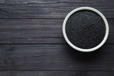 Bowl of black sesame seeds on wooden table, top view. Space for textの写真素材