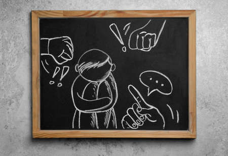 Blackboard with drawn people bullying sad human on gray background, top view