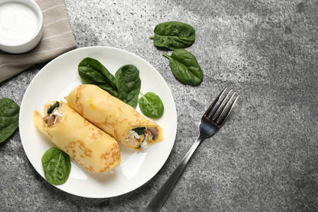 Delicious thin pancakes with chicken and mushrooms on gray table, flat lay