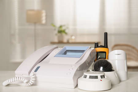Intercom, CCTV camera, walkie talkie, smoke and movement detectors on white table indoors. home...