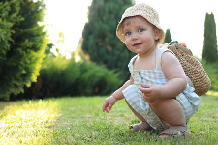 Cute little girl in stylish clothes with knitted backpack outdoors on sunny day. Space for textの写真素材