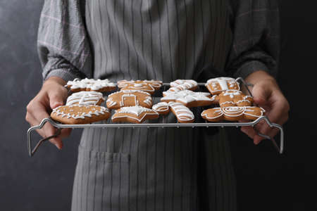 Woman holding cooling rack with delicious homemade Christmas cookies on black background, closeupの写真素材