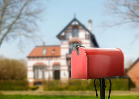 Red letter box and blurred view of modern house with beautiful garden on sunny day, space for textの写真素材