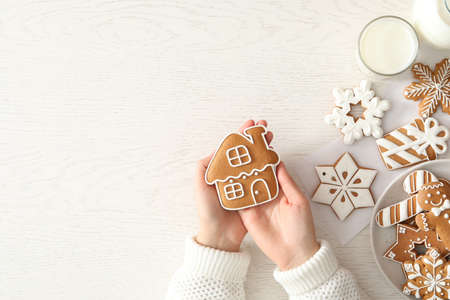 Woman holding delicious homemade Christmas cookie on white table, top view. Space for textの写真素材