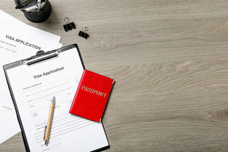 Visa application form, passport and stationery on wooden table, flat lay. Space for textの写真素材