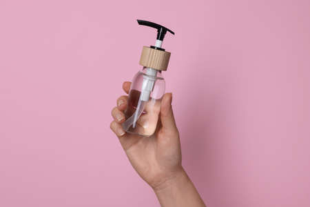 Woman holding bottle of cosmetic product on pink background, closeupの写真素材