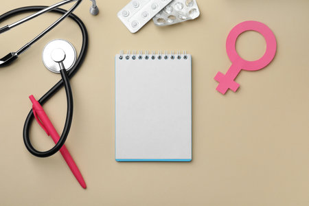 Flat lay composition with female gender sign and stethoscope on beige background. Women's health conceptの写真素材