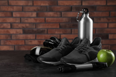Different cycling accessories on black table against brick wall, space for textの写真素材
