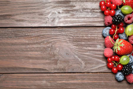 Different fresh berries on wooden table, flat lay. Space for textの写真素材