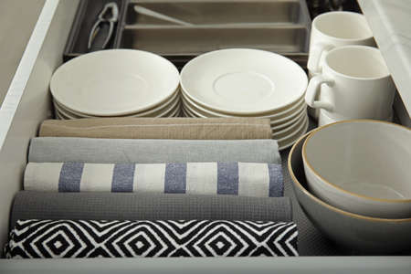 Open drawer of kitchen cabinet with different dishware and towels, closeupの写真素材