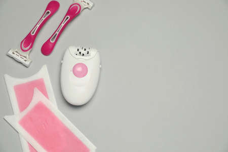Modern epilator, wax strips and razors on light gray background, flat lay. Space for textの写真素材