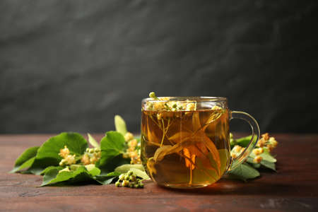 Cup of tea and linden blossom on wooden table. Space for textの写真素材