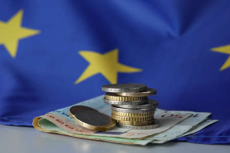 Coins, banknotes and European Union flag on table, closeupの写真素材