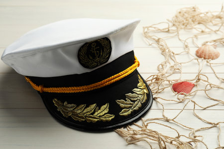 Peaked cap, net and shells on white wooden background, space for textの写真素材