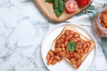 Toast with delicious canned beans on white marble table, flat lay. Space for textの写真素材