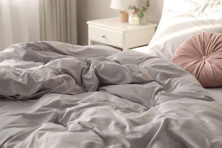 Bed with stylish silky linens in room