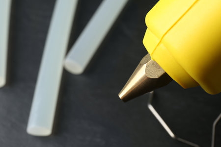 Hot glue gun and sticks on dark gray table, closeupの写真素材