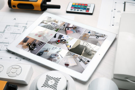 Tablet with view from CCTV cameras and different equipment on white table. home security system