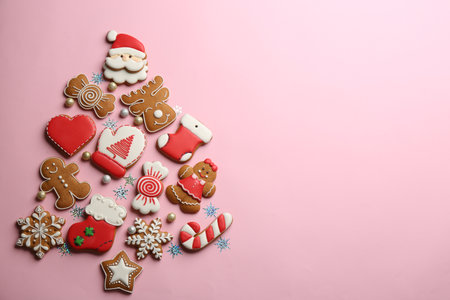 Delicious gingerbread cookies arranged in shape of Christmas tree on pink background, flat lay. Space for textの写真素材