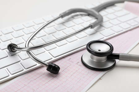 Keyboard, cardiogram paper and stethoscope on beige background, closeupの写真素材