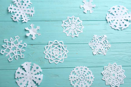 Many paper snowflakes on turquoise wooden background, flat layの写真素材
