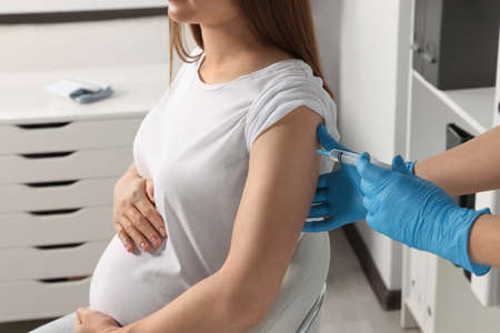 Doctor giving injection to pregnant woman in hospital, closeupの写真素材