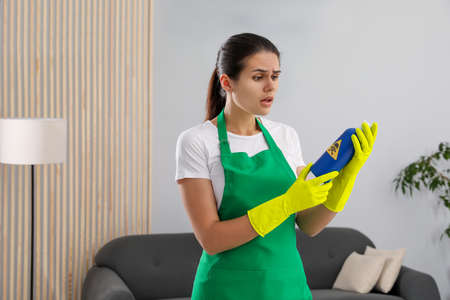 Woman looking at bottle of toxic household chemical with warning sign indoors