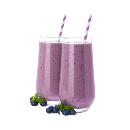 Glasses of blueberry smoothie with fresh berries and mint on white backgroundの写真素材