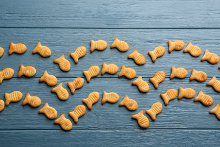 Delicious goldfish crackers on blue wooden table, flat layの写真素材