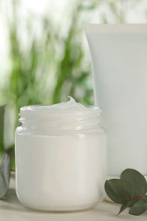 Different hand care cosmetic products and eucalyptus branches on white wooden table, closeupの写真素材