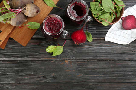 Fresh beet juice and raw vegetable on dark wooden background, flat lay. Space for text