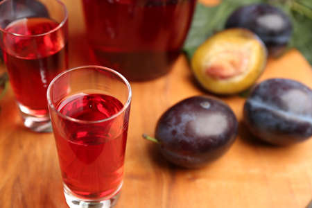 Delicious plum liquor in shot glass on wooden board. homemade strong alcoholic beverageの写真素材