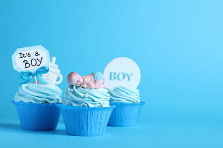 Beautifully decorated baby shower cupcakes with cream and boy toppers on light blue background. Space for textの写真素材