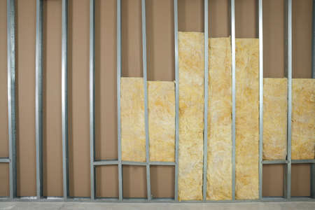 Wall with metal studs and insulation material indoors, space for text