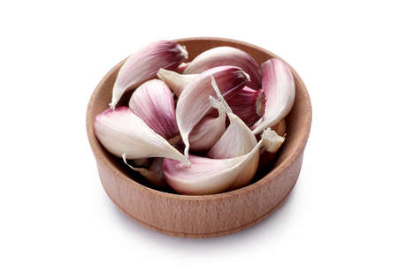 Unpeeled garlic cloves in wooden bowl isolated on whiteの写真素材