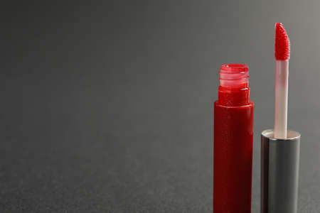 Red lip gloss with applicator on dark background, closeup. Space for textの写真素材