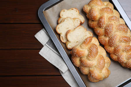 Baking tray with homemade braided bread on wooden table, top view and space for text. Traditional...
