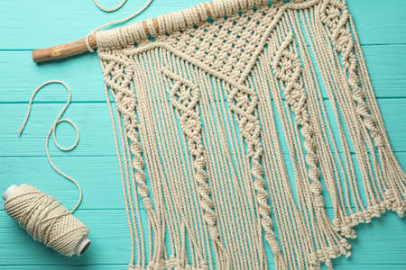 Stylish beige macrame and cord on turquoise wooden table, top view