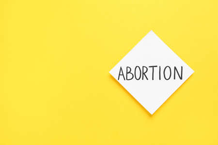 Paper note with word Abortion on yellow background, top view. Space for textの写真素材